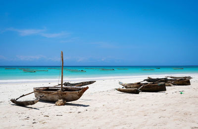 Outrigger boats at beach against sky