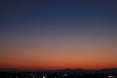 Scenic view of silhouette city against clear sky at sunset