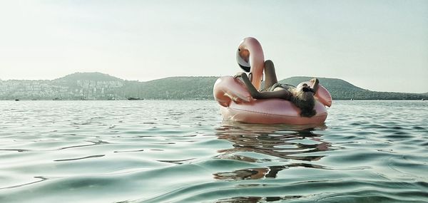 Woman in bikini by sea against sky