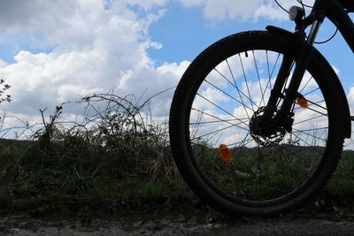 Bicycle wheel on field against sky