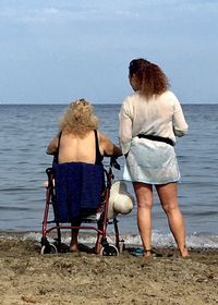 Rear view of women sitting on beach