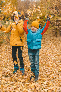 Boys in a jacket scatter leaves in an autumn park. the child rejoices in the autumn leaves. 