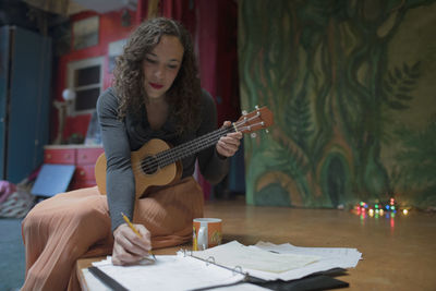 Full length of a young woman sitting on table