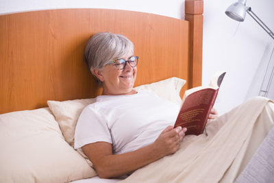 Midsection of man using mobile phone while sitting on bed