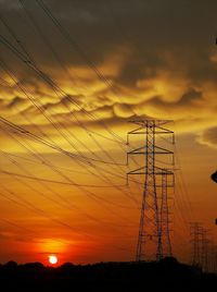 Silhouette electricity pylon against sky during sunset