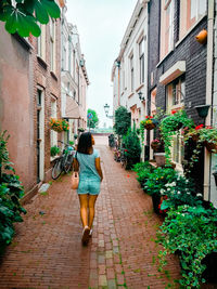 Rear view of woman walking on footpath amidst buildings