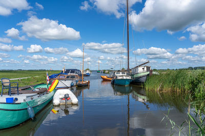 Boats moored at harbor against sky