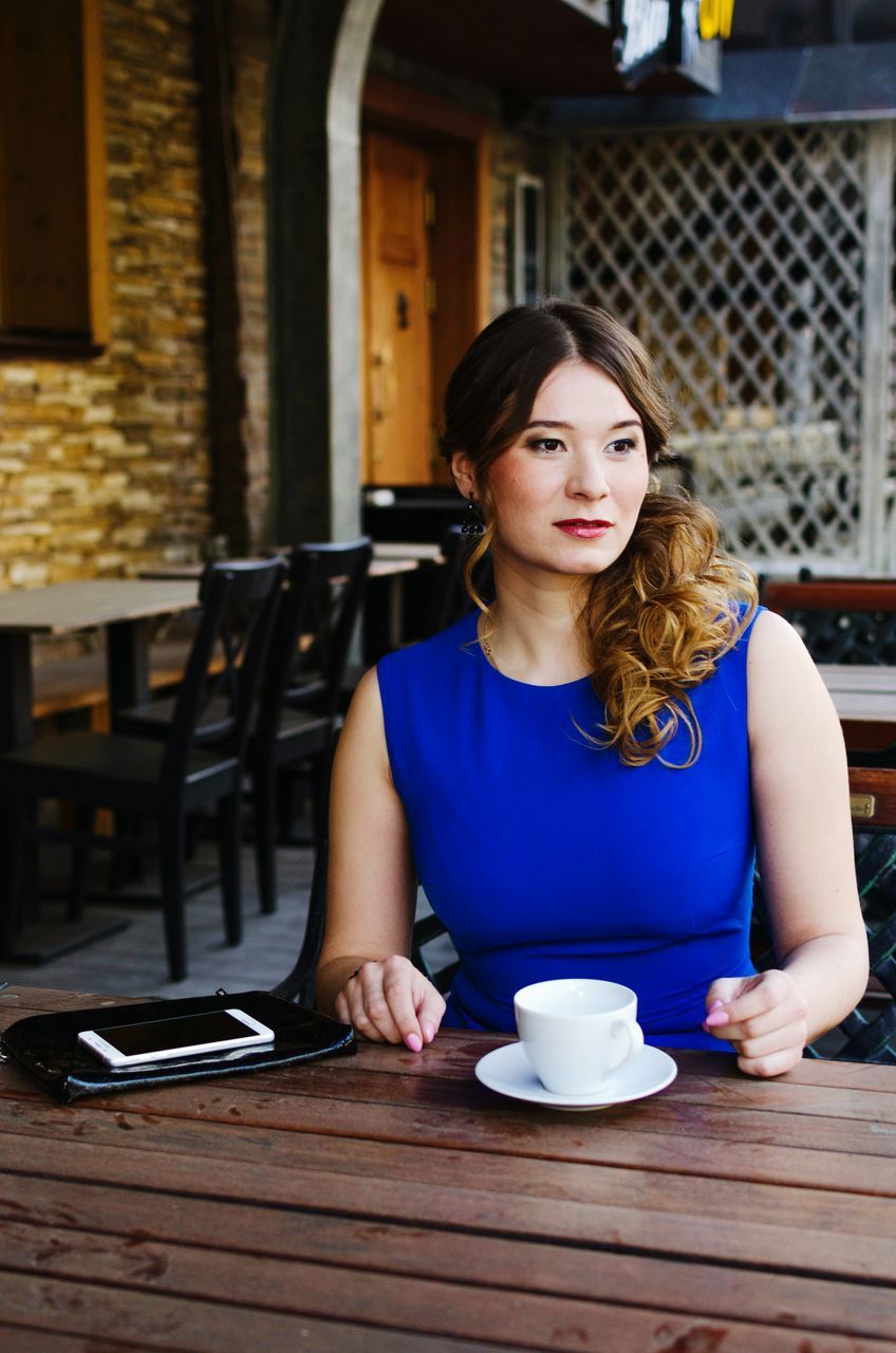 PORTRAIT OF YOUNG WOMAN SITTING ON WALL