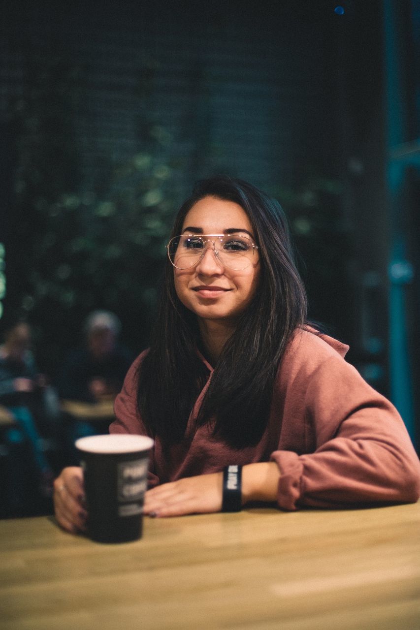 PORTRAIT OF YOUNG WOMAN WITH COFFEE CUP