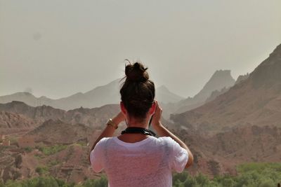 Rear view of woman photographing mountains