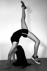 Side view of woman doing yoga against wall