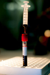 Close-up of blood sample in tube with syringe on tray at laboratory