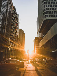City street amidst buildings against sky during sunset