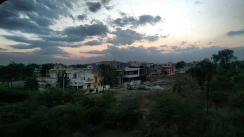 Houses and trees against sky at sunset