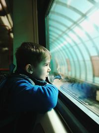 Rear view of boy looking through train window