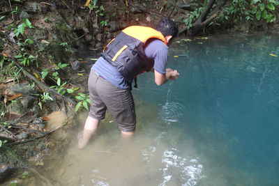 Full length of man standing in lake at forest