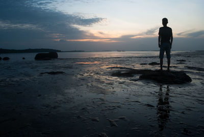 Silhouette man standing on calm beach