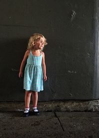 Cute girl standing on street against wall