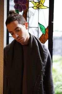 Portrait of young man standing by window