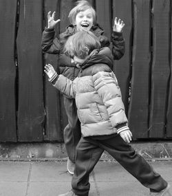 Boys playing against wooden fence