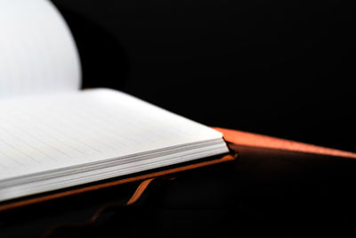 Close-up of open book on table against black background