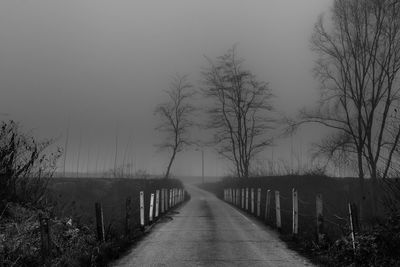 Road amidst bare trees against sky during winter