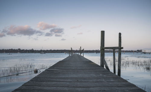 Wooden pier over lake against sky