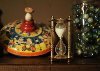 Hourglass with toy and marbles in jar on table at home