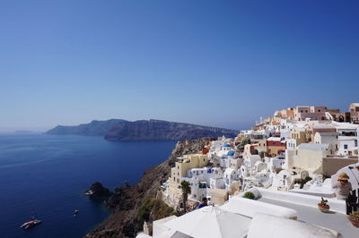 Buildings by sea against clear blue sky at santorini