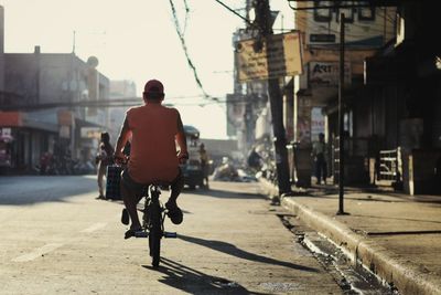 Rear view of man riding bicycle on road