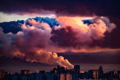 Smoke emitting from factory against sky during sunset