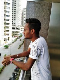 Side view of young man standing in balcony