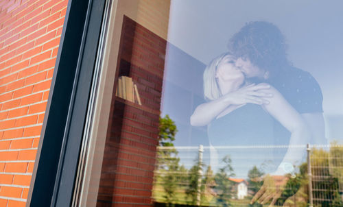 Young woman looking through window in city