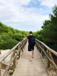 Rear view of man walking on footbridge