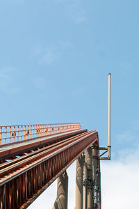 Low angle view of rollercoaster bridge against blue sky