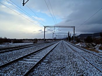 Railroad tracks against cloudy sky during winter