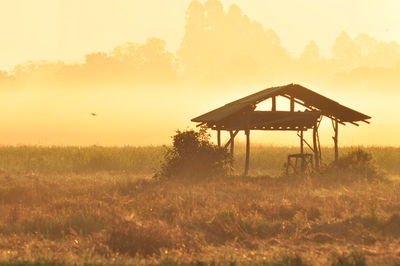 Silhouette gazebo on field against clear sky at sunset