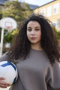 Teenage girl holding football and looking at camera