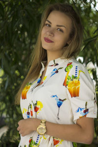 Portrait of smiling young woman standing against plants