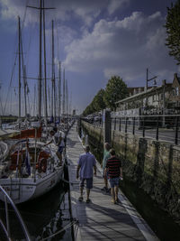 Sailboats moored at harbor against sky