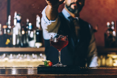 Midsection of bartender preparing cocktail in bar