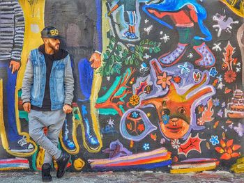 Full length of man standing against graffiti wall