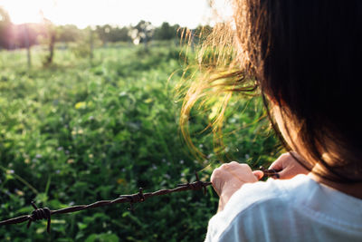 Rear view of child holding barbed wire