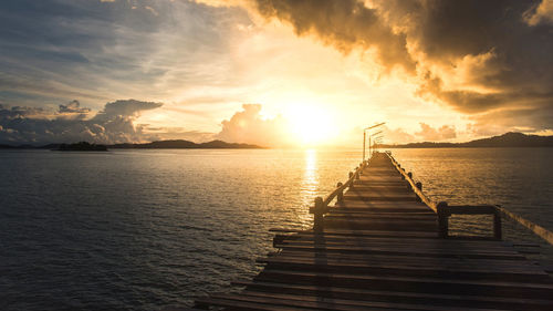 Pier over sea against sky during sunset