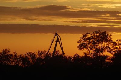 Low angle view of electricity pylon against sky during sunset