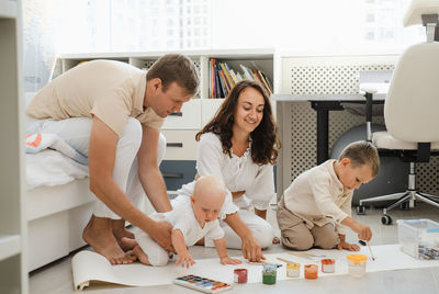 Parents with two kids painting on the floor on big roll of paper. develop child creativity and