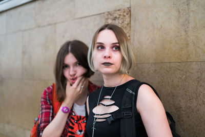 Females friends standing by retaining wall