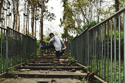 Young man jumping over steps against trees