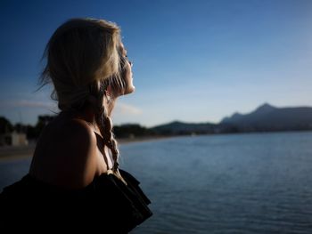 Rear view of woman looking at lake against sky