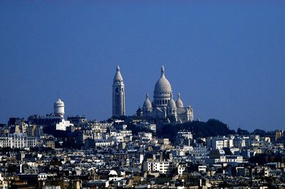 View of buildings in city against clear blue sky